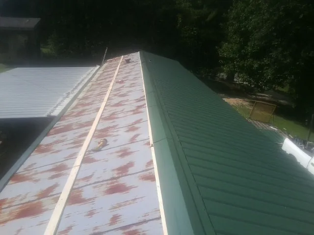 Old rusted panels beside newly installed green metal roofing — Wind Damage Roof Repair by Roofing Brothers in Ririe