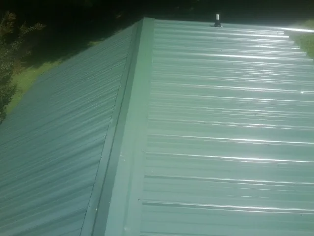 New green metal panels meeting at the ridge of a roof — Flat Roof Repair work by our crew in Ririe