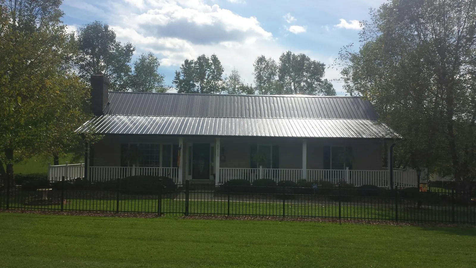 Gray metal roof on a brick ranch with a full width front porch — Gutter Guard Installation work by our crew in Ririe