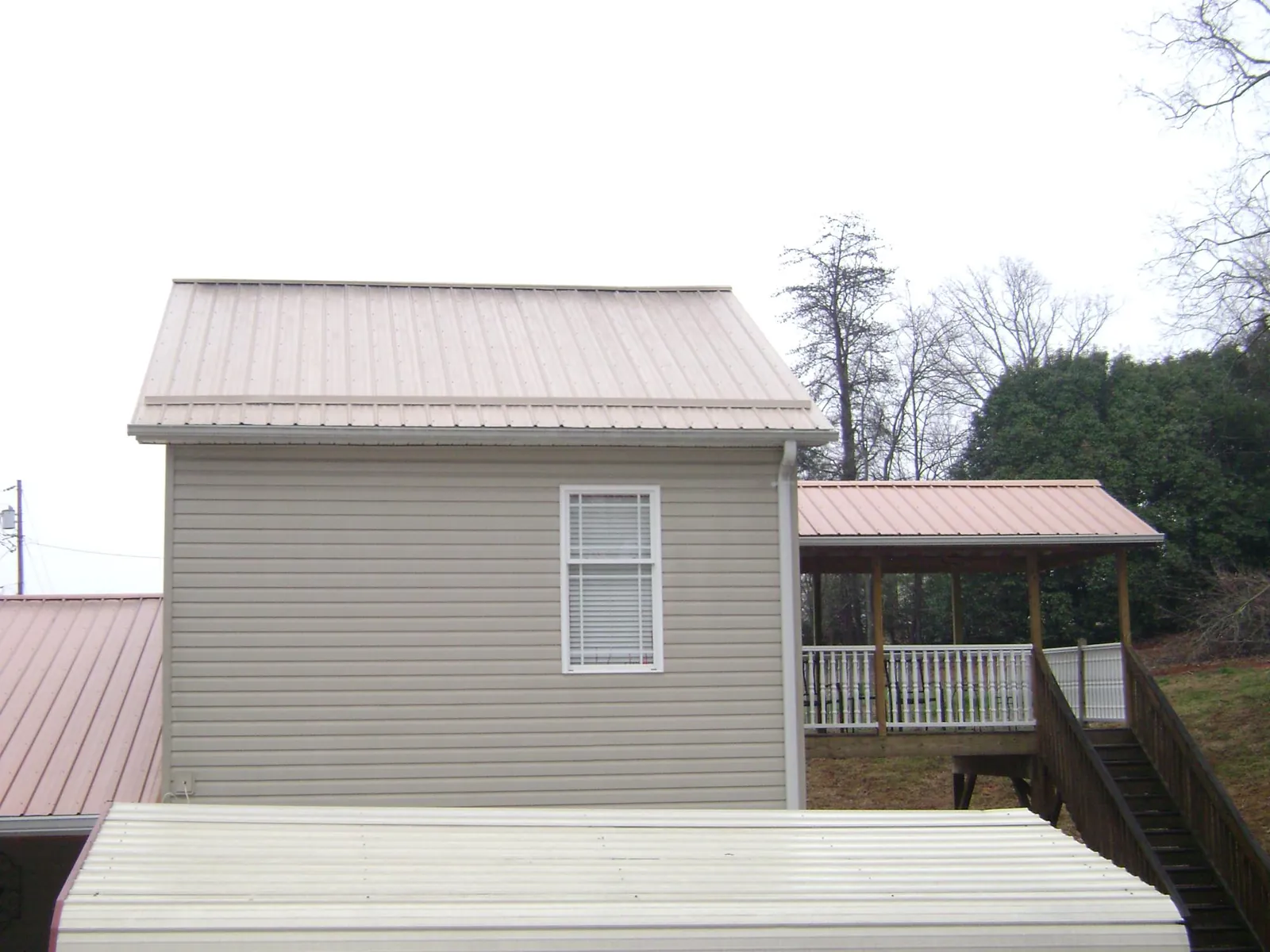 Tan metal roofs on a two story addition and attached porch, from a Roof Replacement job in Ririe
