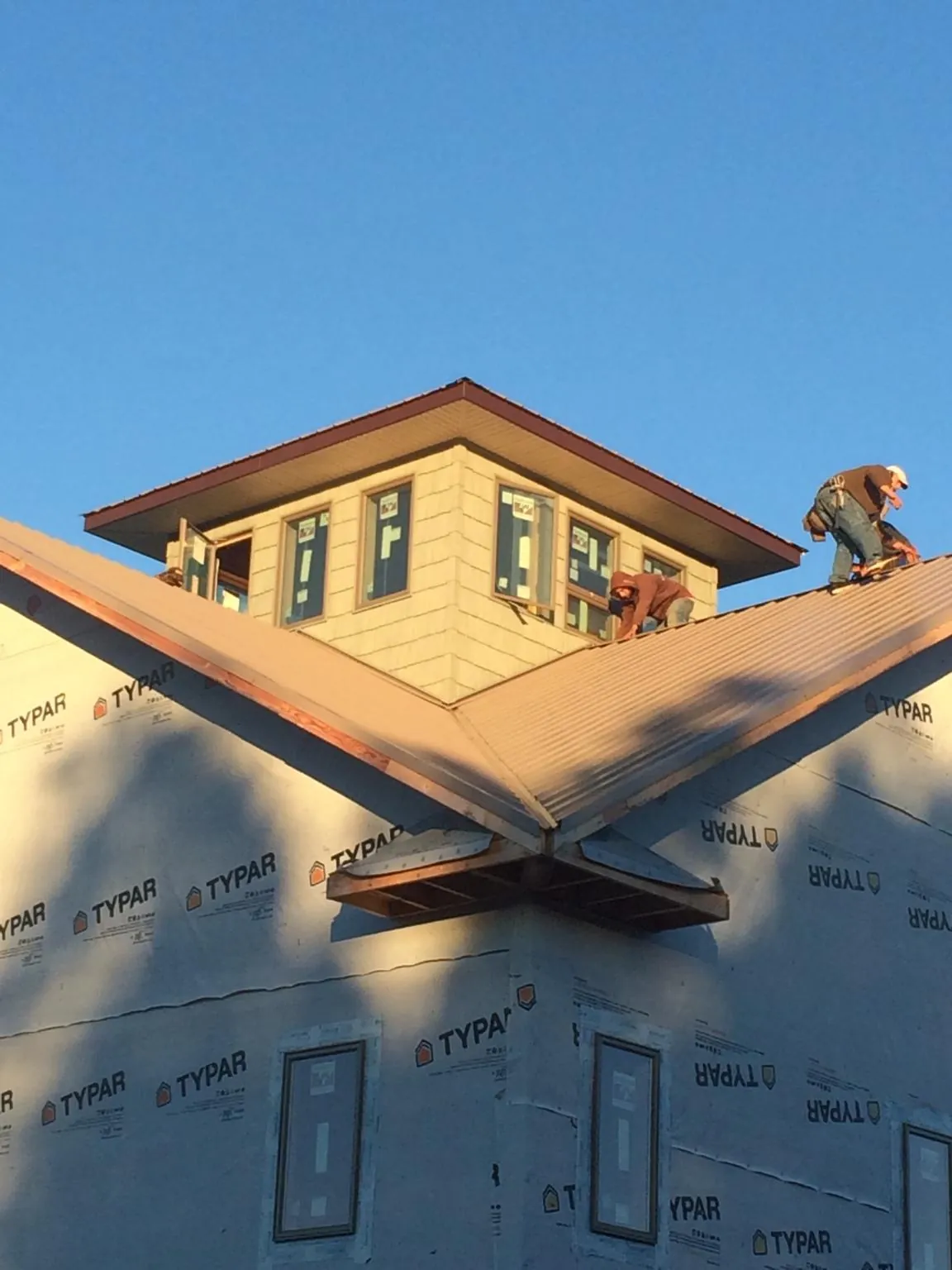 Roofers working around a rooftop cupola on a new metal roof at sunset — Roof Waterproofing in Ririe by Roofing Brothers